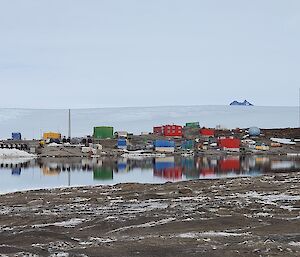Mawson station in the mid-ground with reflections of the station in the bay in front.