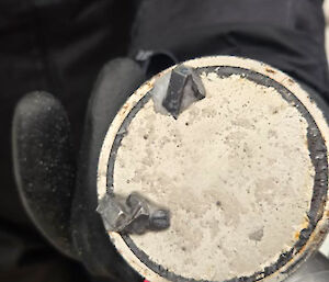 A circular magnet with two triangular pieces of metal stuck to it.