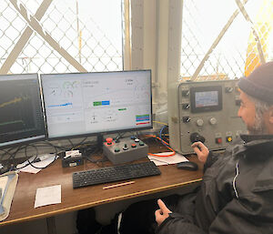 A man monitors information on a computer monitor.