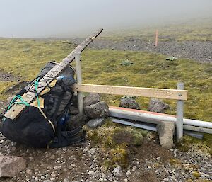 A newly installed track sign (Tiobunga Lake Track) next to a backpack with the old sign strapped to it.