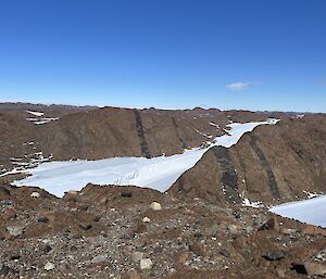 A very large grey-brown rock, marked with black stripes sits in a frozen area.