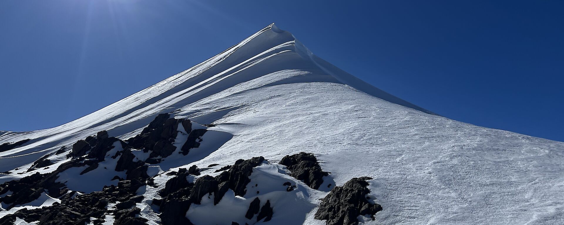A snowy peak rises into a deep blue sky