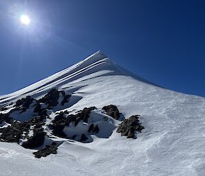 A snowy peak rises into a deep blue sky