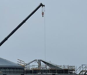 A crane lowers a metal section into the skeleton or a domed roof.