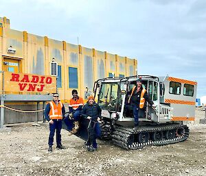 Four individuals pose on top of a vehicle in front of the Casey station OPs Building