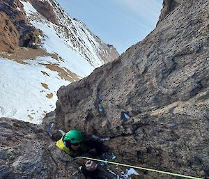 An expeditioner climbing a steep exposed mountain in Antarctica.