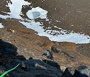 An expeditioners on a rope climbing a steep mountain.