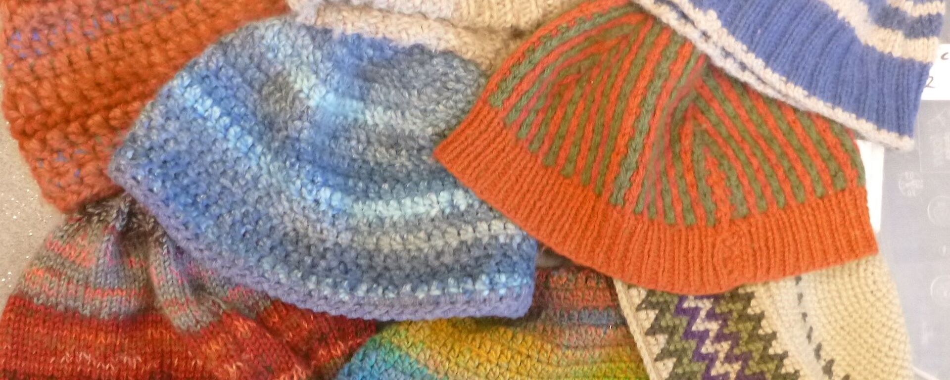A picture of eight differently coloured handmade beanies including all the ones described in the article.