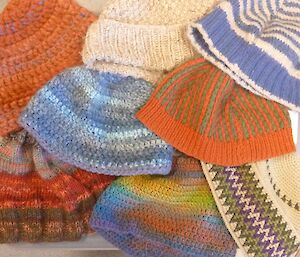 A picture of eight differently coloured handmade beanies including all the ones described in the article.
