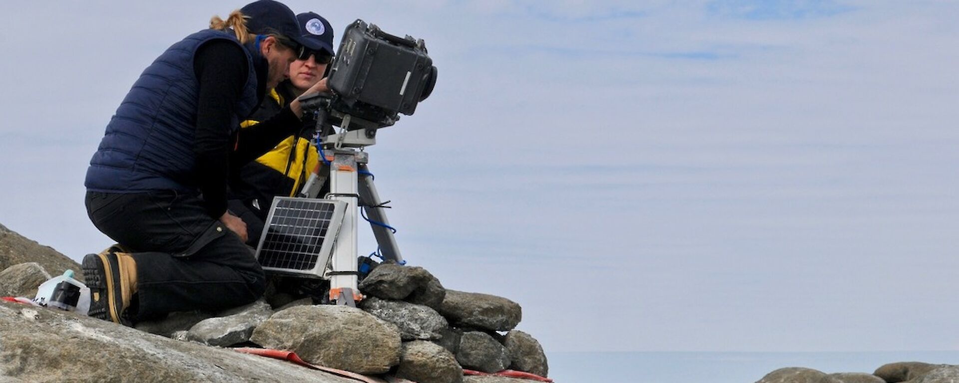 A man and a woman sitting next to a camera on a tripod