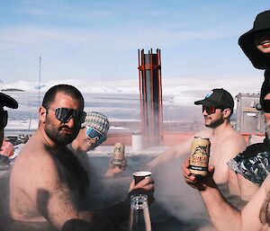 A group of people with drinks in a hot tub.