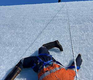 A headless dummy dressed in high vis clothing at the bottom of a slope, beside a rope running from the top of the slope.