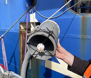 A small plastic ball with holes in it tied to the end of a pip with zip ties.