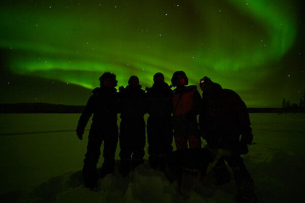 5 people silhouette foreground to a vibrant Aurora Borealis